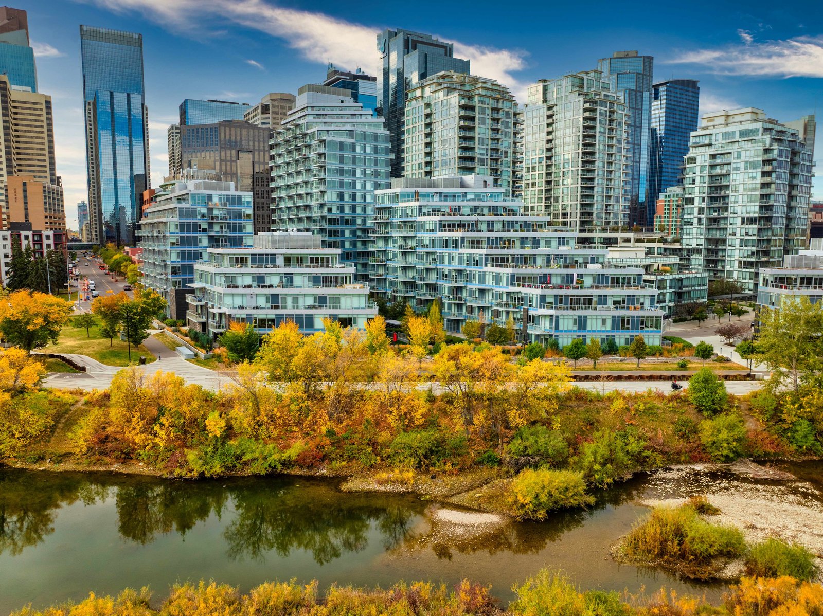 Waterfront buildings beside the Bow River and autumn trees