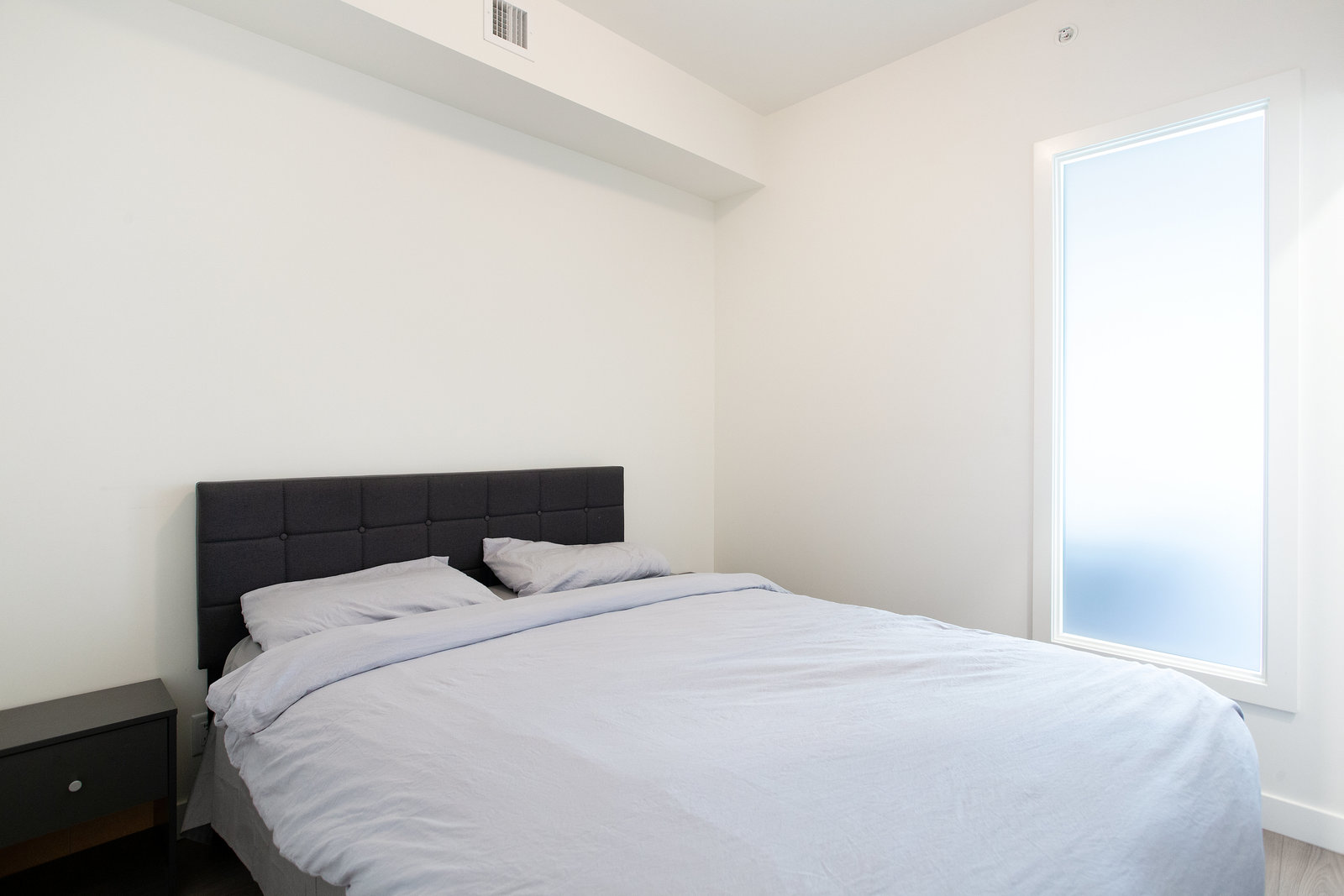 Bedroom with dark headboard and frosted-glass door